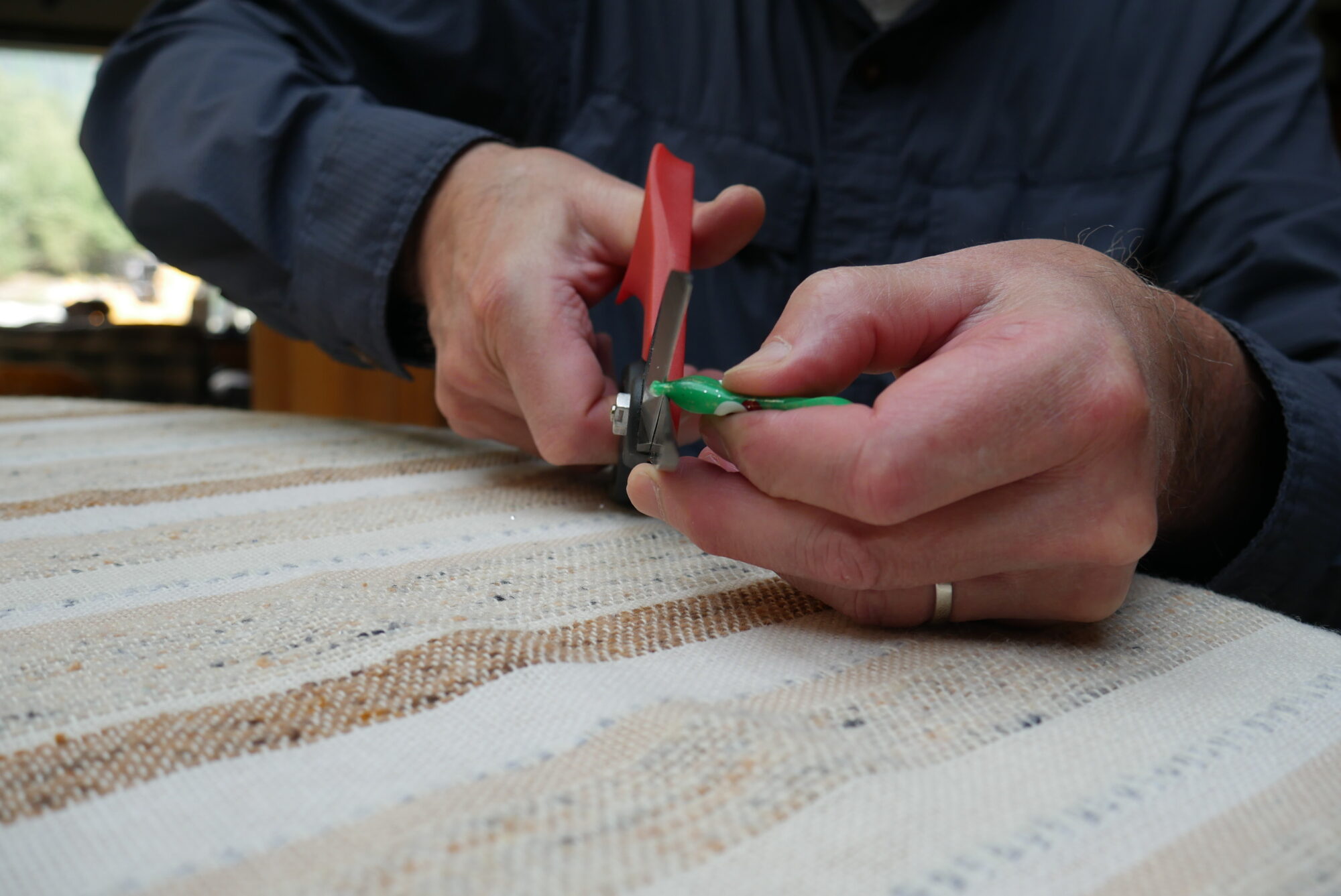 Cutting the nose hole in a green plastic squid skirt